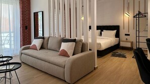 Ein modernes Hotelzimmer mit einer Couch, einem Bett, einem kleinen Tisch und einem Stuhl.