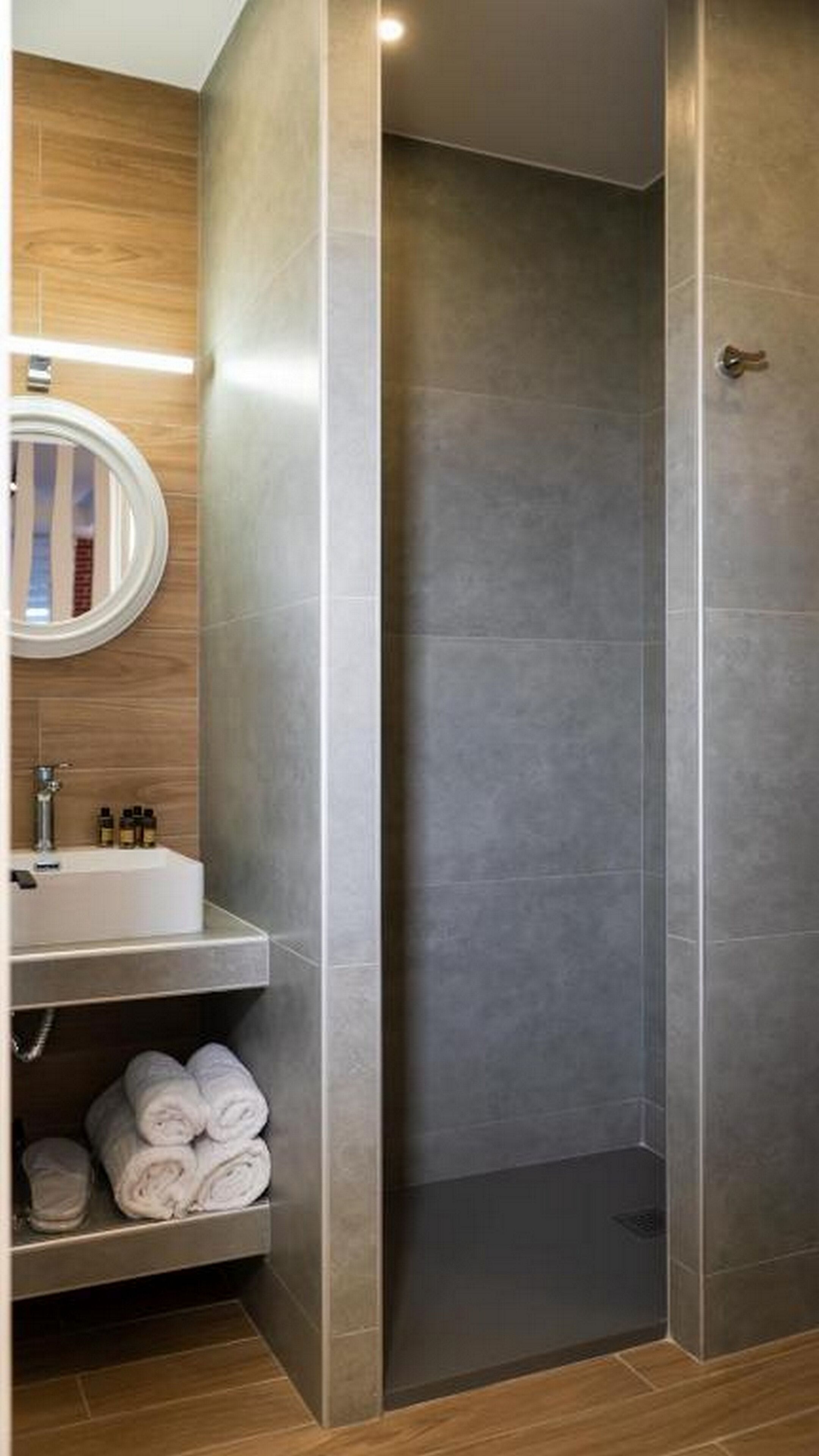 A modern bathroom with a shower, a sink with toiletries, and a mirror.