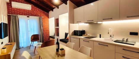 Una cocina moderna con armarios blancos, una mesa de comedor de madera y una pared de ladrillo.