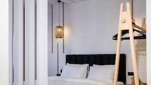 Ein modernes Schlafzimmer mit einem Bett, einer Hängeleuchte und einer Holzleiter.