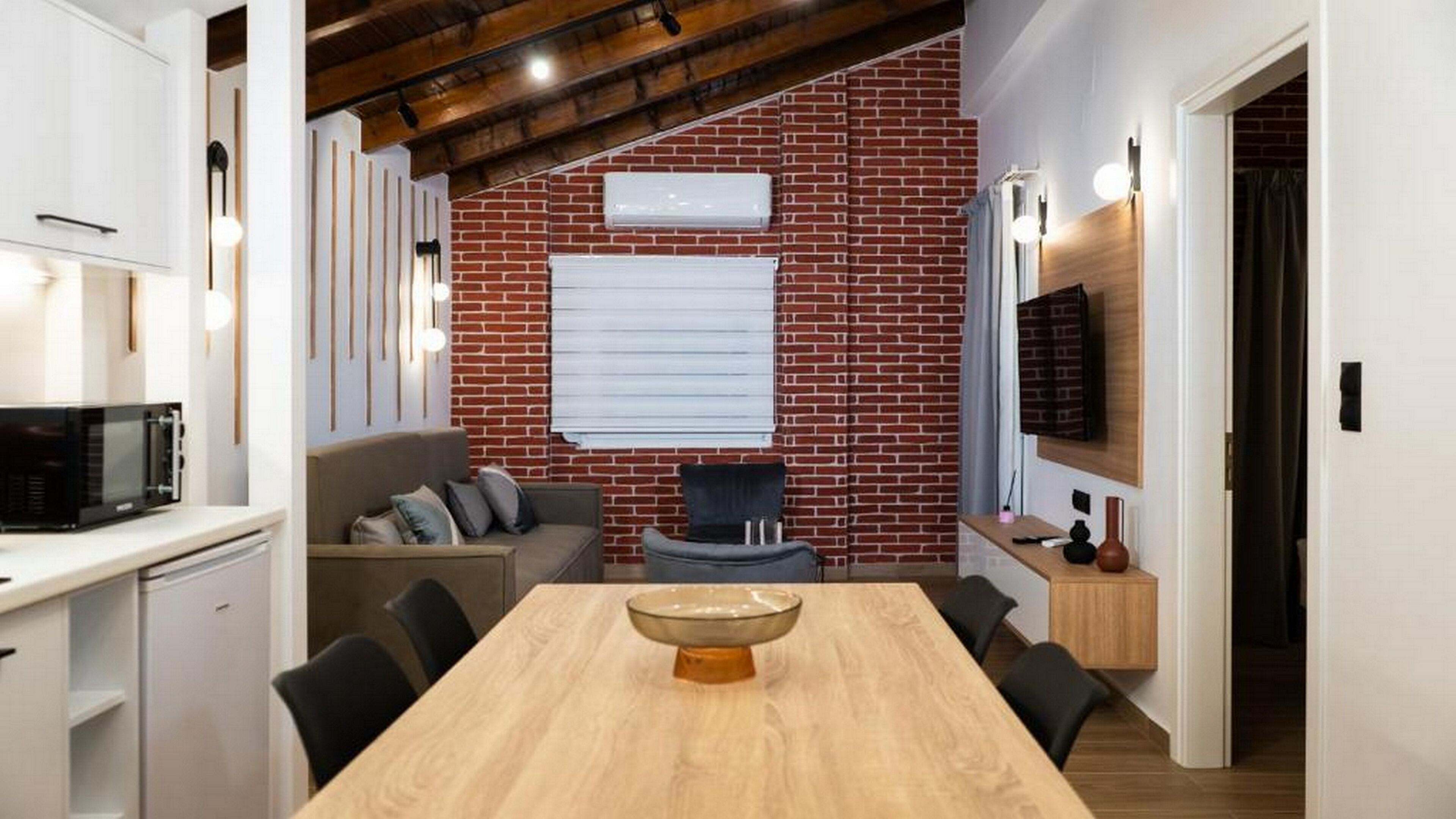 Una cocina moderna con pared de ladrillo, una mesa de comedor de madera y un microondas negro.