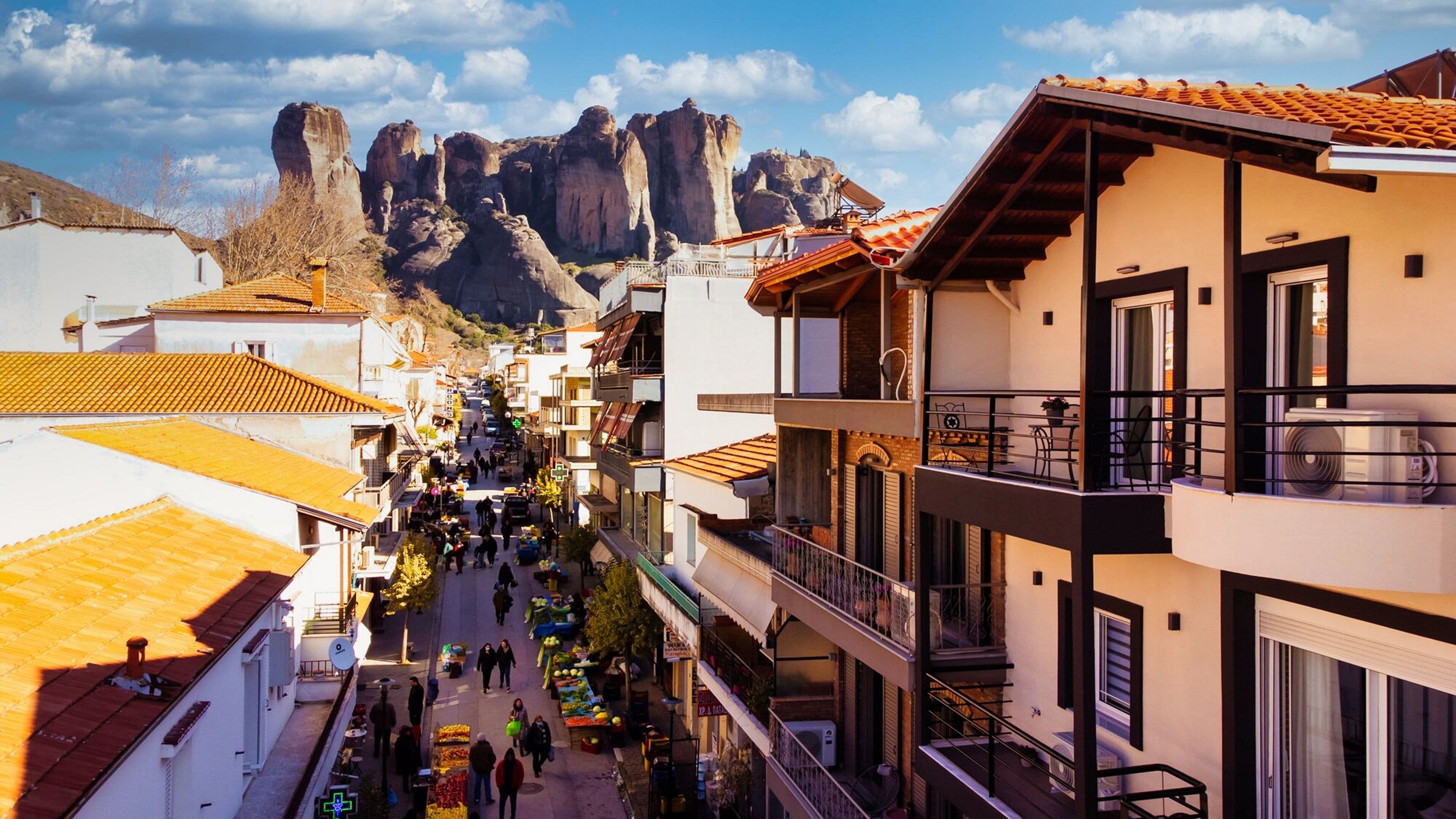 Uma rua com edifícios, varandas e uma montanha ao fundo.
