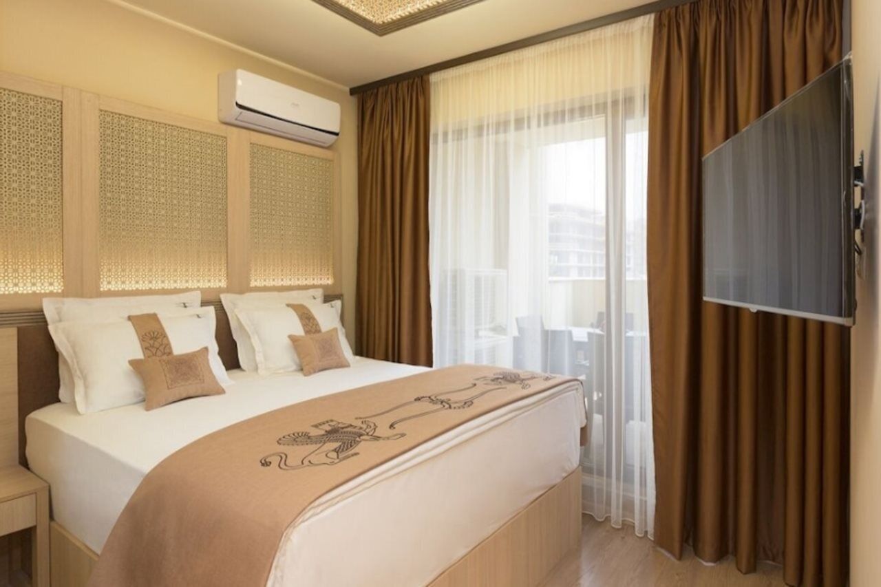 Een hotelkamer met een groot bed, een flatscreen televisie en een raam met dunne gordijnen.