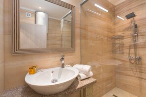 Une salle de bain avec un grand miroir, un lavabo et une douche.