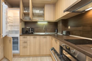 A compact kitchen with wooden cabinets, a built-in oven, a microwave, a coffee maker, and a toaster. - Argisht Partez (Varna)