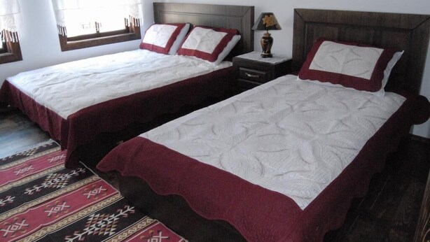 Two single beds with red and white bedding, wooden headboards, and a nightstand with a lamp. - Hotel Belgrad Mangalem (Berat)