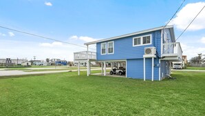 Une maison bleue avec un porche abrité et un petit garage attenant.
