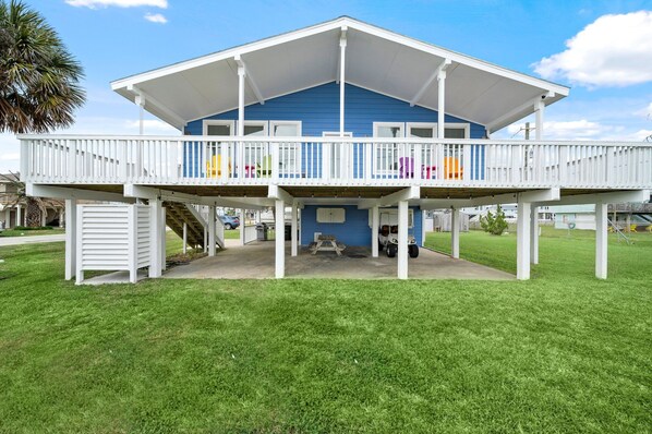 Ein zweistöckiges Haus mit Balkon, überdachter Veranda und kleiner Terrasse.