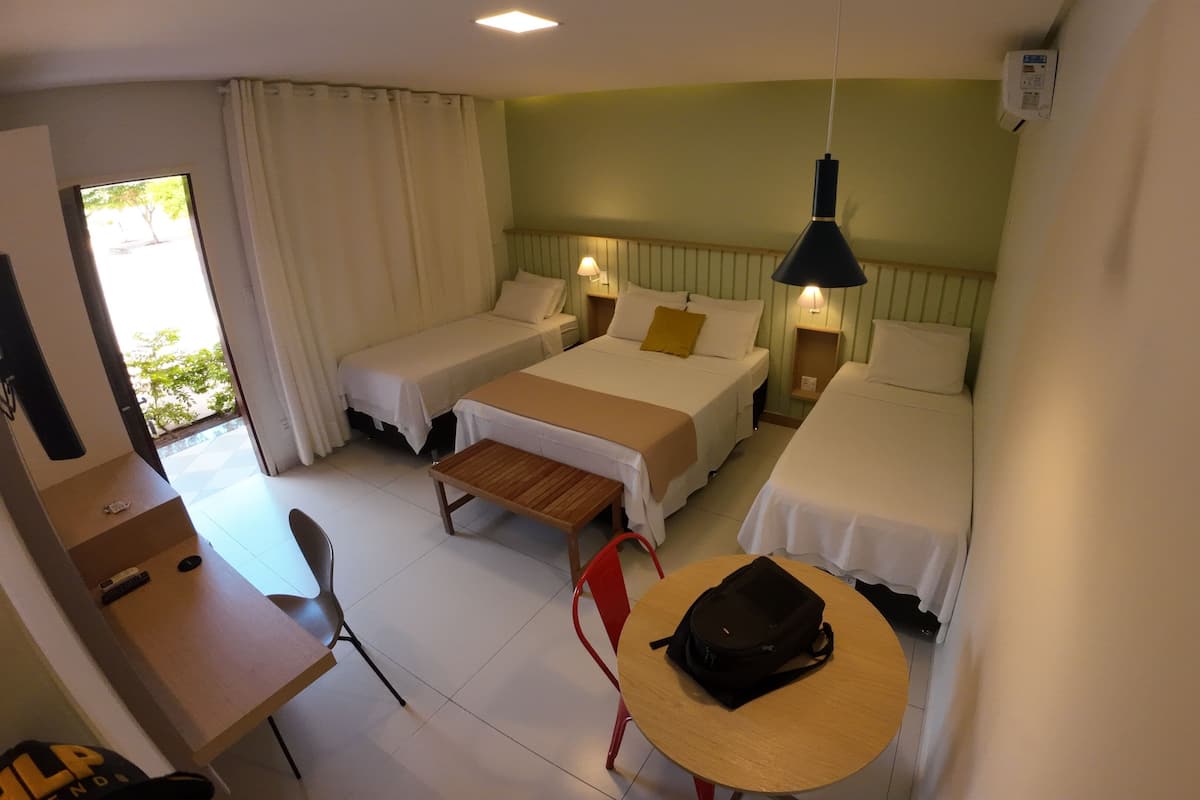 Ein Hotelzimmer mit zwei Einzelbetten, einem kleinen Tisch, einem Stuhl und einer Hängelampe.