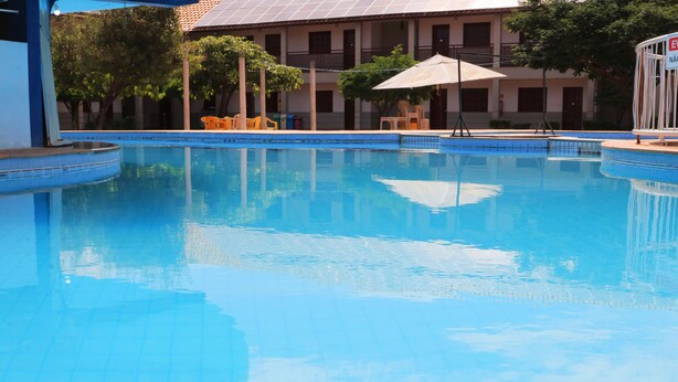 A swimming pool with a tiled edge, surrounded by outdoor seating and a building with multiple windows. - Hotel Pousada da Lapa (Bom Jesus Da Lapa)