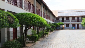 A courtyard with a cobblestone path, a building with a balcony, and a solar panel roof. - Hotel Pousada da Lapa (Bom Jesus Da Lapa)
