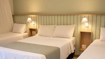 Habitación de hotel con dos camas, una mesita de noche de madera, una silla roja y un jarrón con flores secas.