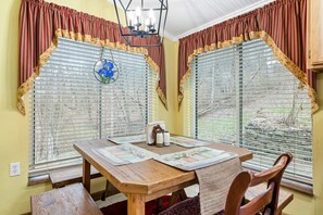 Enjoy meals in this cozy dining area with a table for two, a bench, and a floral-patterned placemat.