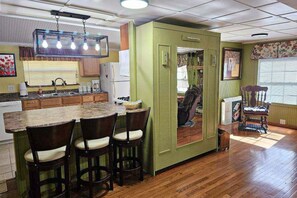 Enjoy meals in this kitchen with an island and bar stools, adjacent to a dining area with a rug and chair.