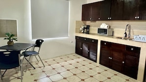 Una cucina compatta con zona pranzo, dotata di microonde, macchina del caffè e lavello.
