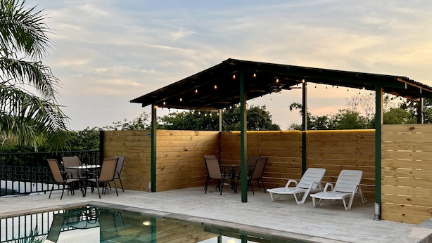 Area piscina con zona relax coperta, poltrone da sdraio e piscina.
