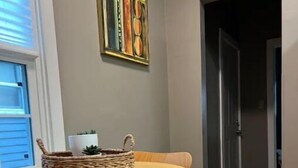 A dining area with a round table and two chairs, a woven basket with a plant, and a framed artwork on the wall. - IU Medical Campus Convenience (Indianapolis)