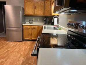 Una cocina con armarios de madera, un refrigerador de acero inoxidable, estufa y microondas.