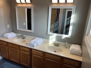 Bathroom features a dual sink vanity with two large mirrors and wooden cabinets.