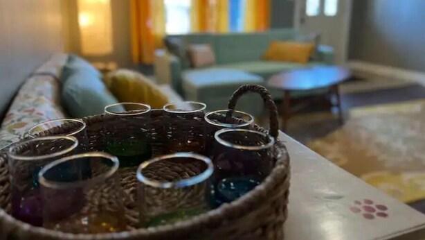 A wicker basket with multiple glasses on a table in a cozy living room. - IU Medical Cozy Campus Castle (Indianapolis)