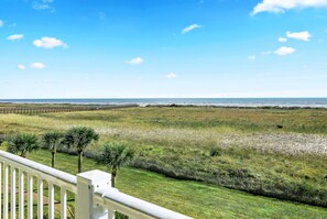 A coastal view with a grassy area, palm trees, and a wooden fence. - Mermaid Cove -Beach Front - Top Floor -2BD/2BA. Sleeps 6 (Galveston)