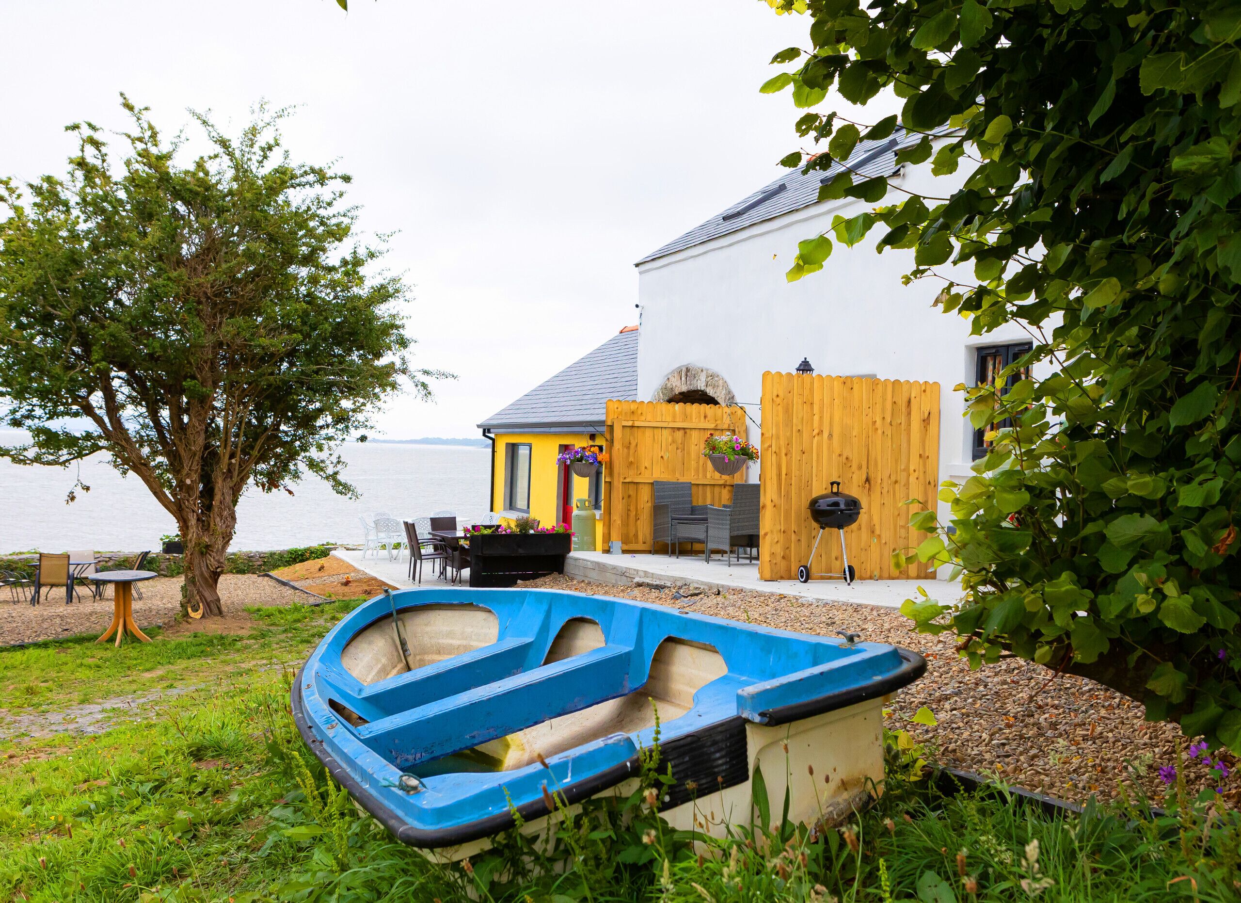 A house with a wooden deck, a barbecue, and a boat in the foreground.