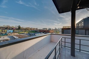 A rooftop terrace with a view of a cityscape, including buildings and a parking lot.