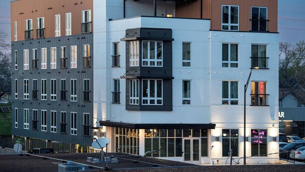 A multi-story building with a mix of window styles and a ground-level entrance with a glass facade.