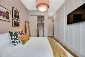 A bedroom with a bed, a wardrobe, a television, and a closet.