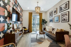 A modern living room with a sofa, a coffee table, a TV, and a patterned wall.