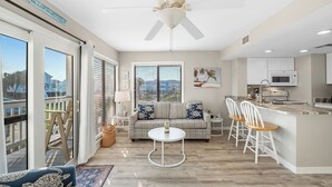 A spacious living area with a sofa, a round table, and a kitchen with a microwave. - Gulf Shores Plantation-West 1240 (Gulf Shores)