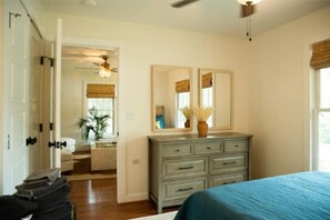 A bedroom with a bed, a dresser, a mirror, and a ceiling fan.