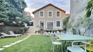 Un giardino con tavolo e sedie, un prato e un edificio sullo sfondo.