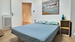 Una camera da letto con un letto, una porta, un piccolo armadio e un quadro appeso al muro.