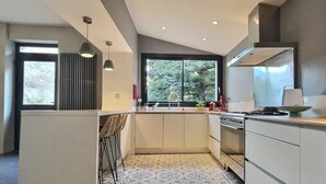 Una cucina moderna con forno integrato, un'ampia finestra e un'isola con sgabelli da bar.