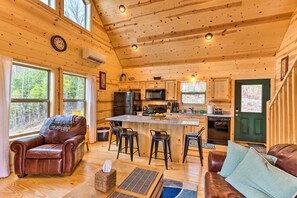Cozy cabin interior with a central kitchen, leather sofa, and dining area.