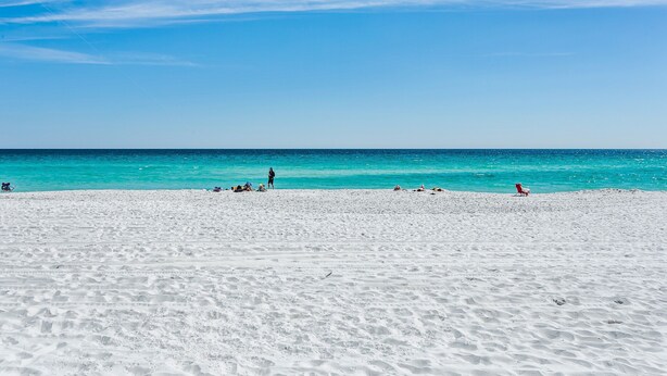 Une plage de sable blanc bordée d’une eau turquoise cristalline.