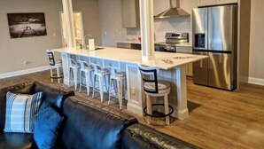 Una cucina moderna con isola centrale, elettrodomestici in acciaio inossidabile e sgabelli da bar.
