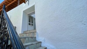 A white building with a stone staircase leading to a door with a window. - Nionas Cheerful House (Piso Meria)