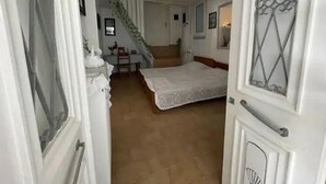 A bedroom with a bed, a desk, and a chair. There is a staircase leading to another room. - Nionas Cheerful House (Piso Meria)