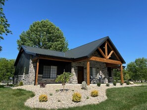 A modern house with a stone facade, a wooden porch, and a landscaped front yard.