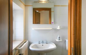 Een badkamer met een wit wastafelmeubel, een spiegel erboven en een handdoek aan de muur.
