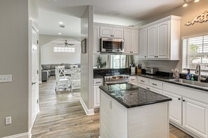 Une cuisine moderne avec des meubles blancs, un îlot central, un four à micro-ondes et une cuisinière.