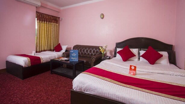 A hotel room with two beds, a sofa, a coffee table, and an air conditioning unit. - OYO 161 Ram Janaki Hotel (Kathmandu)