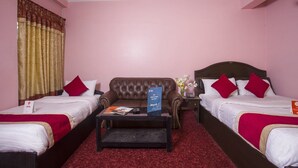 A hotel room with two single beds, a brown sofa, a small table, and a red carpet. - OYO 161 Ram Janaki Hotel (Kathmandu)