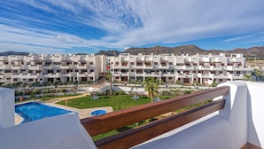 A modern hotel with multiple balconies, a swimming pool, and a mountain backdrop. - Apartamento Calma (Mar de Pulpi) (San Juan de los terreros)