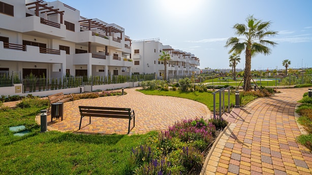 A modern residential complex with multiple balconies, a paved walkway, and a palm tree. - Apartamento Calma (Mar de Pulpi) (San Juan de los terreros)