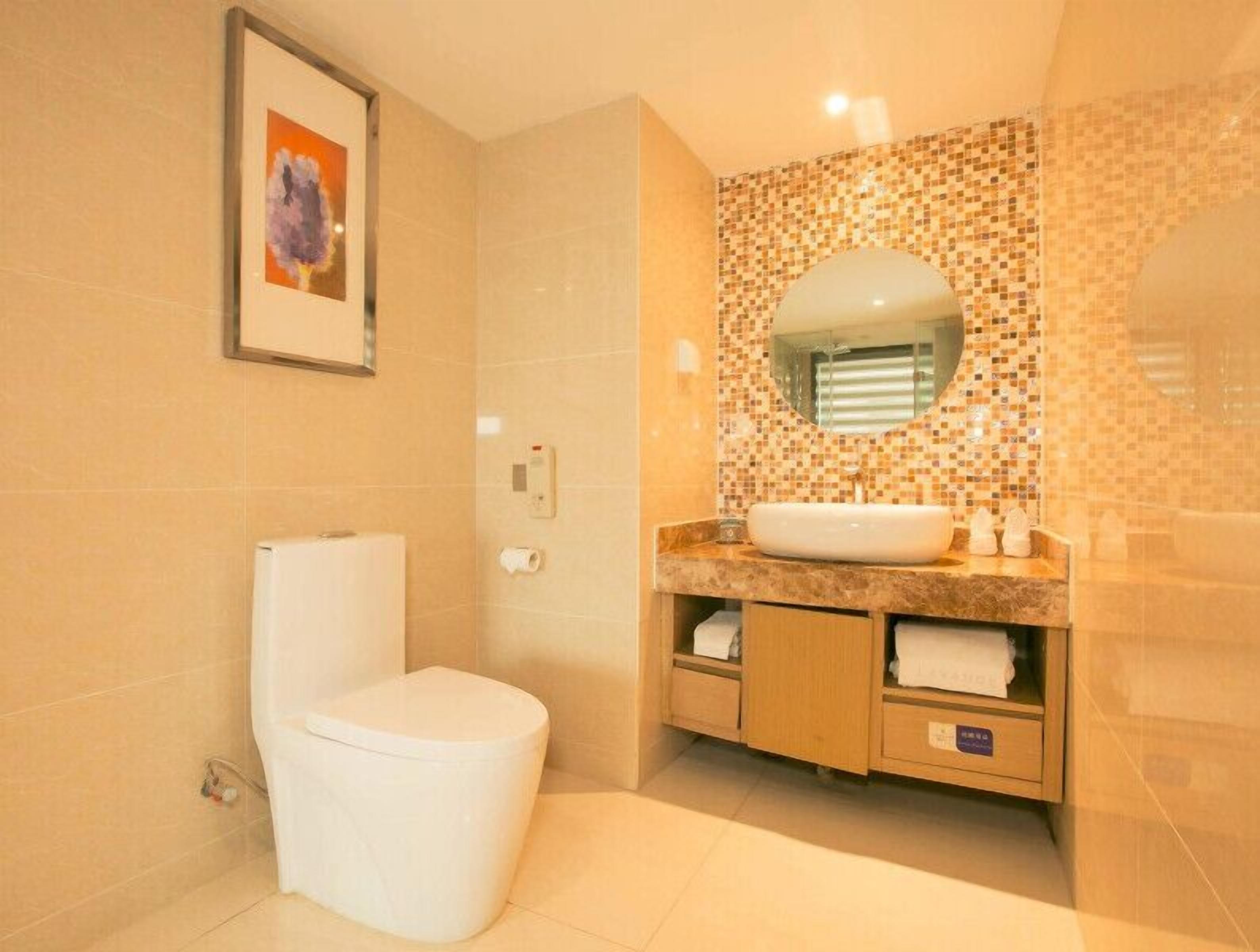 A bathroom with a toilet, sink, and tiled walls.