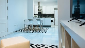 Une cuisine moderne avec des meubles blancs, un coin repas comprenant une table et des chaises, et une grande fenêtre.