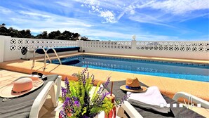 Un espace piscine comprenant des chaises longues, un escalier pour la piscine et une clôture décorative.